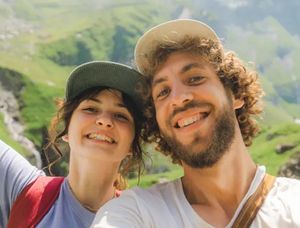 Un couple souriant dans un paysage de collines pittoresques lors d'une aventure estivale, idéal pour trouver des légendes de photos d'été pour Instagram ou un livre photo Photobox.