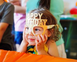 Une petite fille portant un masque "Joyeux anniversaire" doré.