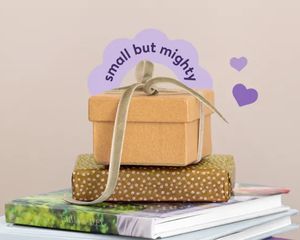 Une pile de livres photo Photobox avec un cadeau emballé posé dessus, pour inspirer des petits cadeaux personnalisés et des idées de cadeaux photo attentionnés.