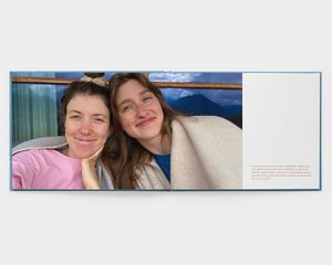 Un livre à ouverture à plat, au format paysage, ouvert sur une photo de deux femmes souriantes.