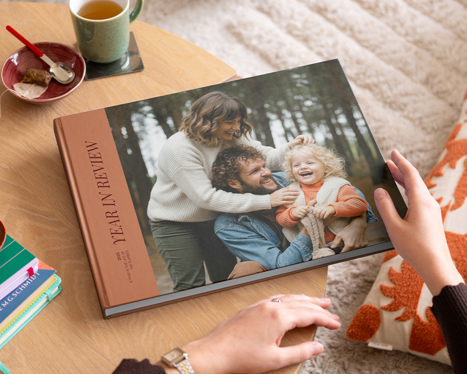 Un livre photo Photobox de type beau livre retraçant l’année, avec une belle photo de famille en couverture, posé sur une table basse comme source d’inspiration pour un livre photo décoratif personnalisé.