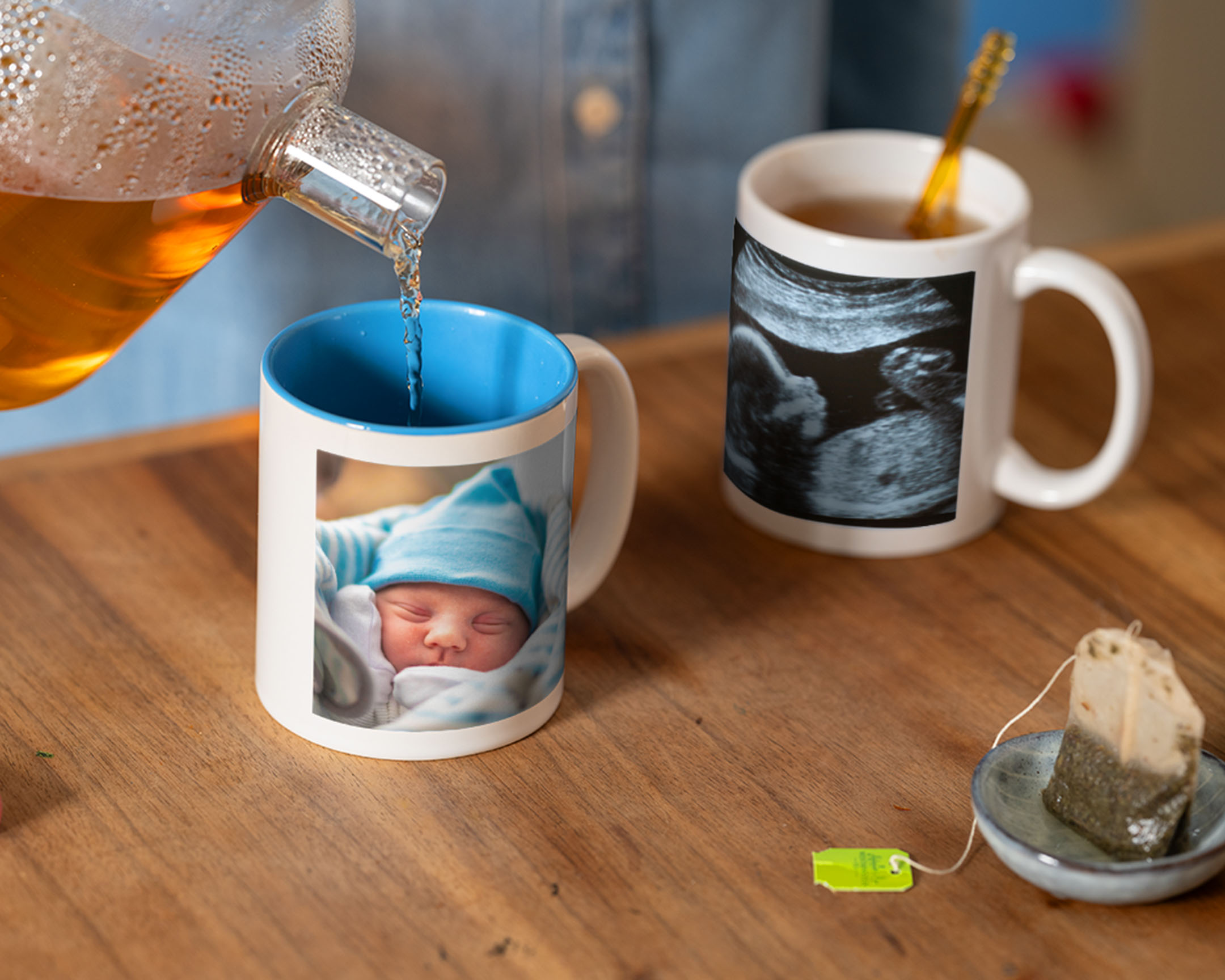 Thé versé dans un mug photo personnalisé avec photo de bébé, à côté d'un autre mug orné d'une échographie.