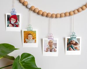 Photos de bébé accrochées à une guirlande suspendue au mur.