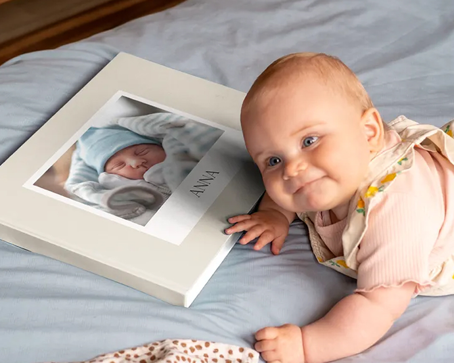 Bébé allongé à côté d'un livre photo personnalisé avec sa photo en couverture.