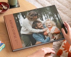Un livre photo Photobox de type beau livre retraçant l’année, avec une belle photo de famille en couverture, posé sur une table basse comme source d’inspiration pour un livre photo décoratif personnalisé.