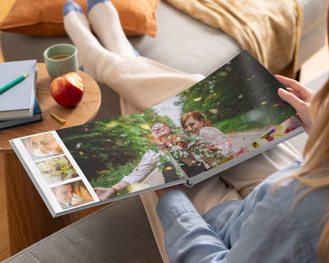 Femme regardant un livre photo à ouverture à plat contenant des photos de mariage.