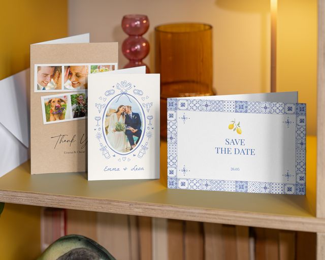 Trois cartes de mariage personnalisées sur une étagère : un save-the-date et deux cartes de remerciement.