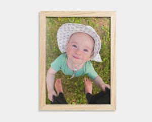 Un poster avec cadre en bois, représentant un bébé sur fond orange.